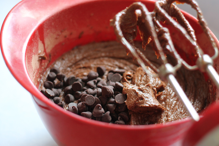 Brownie batter in a red bowl with chocolate chips