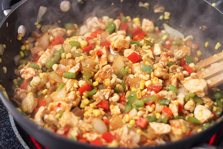 Chicken and vegetables cooking in a skillet