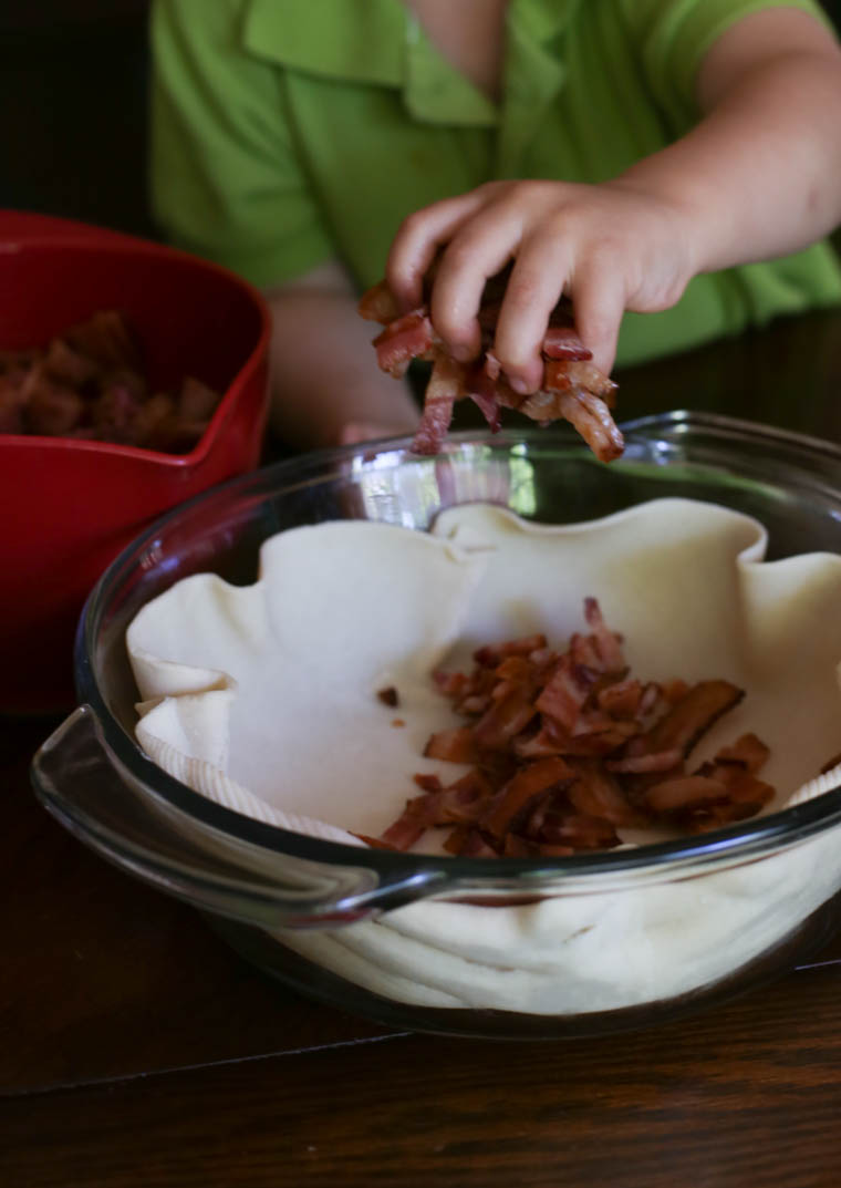 boy's hand putting bacon in a pie crust