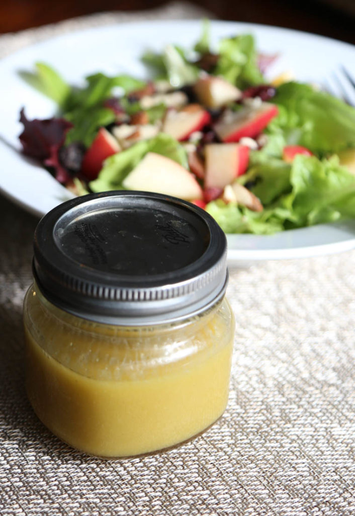 Homemade honey dijon dressing in a jar with a lid on. 