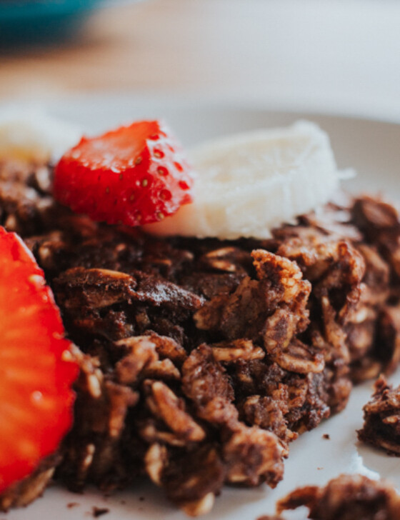 Serving of Dark Chocolate Banana Baked Oatmeal on a plate with sliced strawberries and bananas.