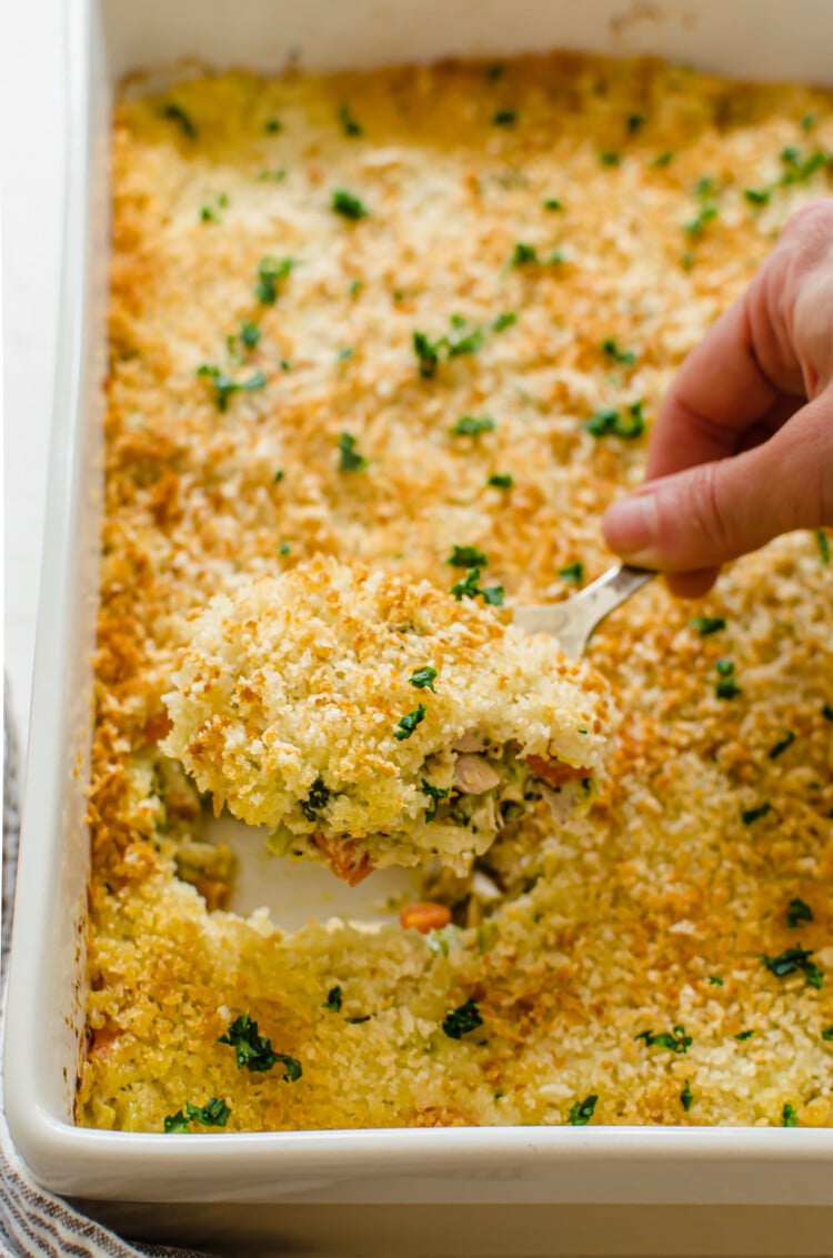cheesy chicken and rice casserole being scooped out of casserole dish.