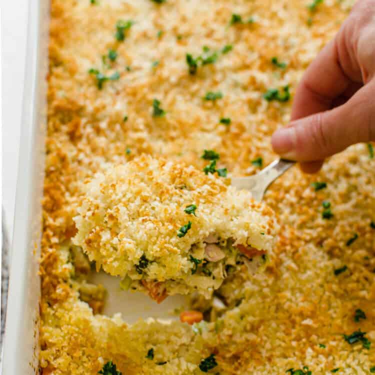 Cheesy chicken and rice casserole being scooped out of casserole dish.