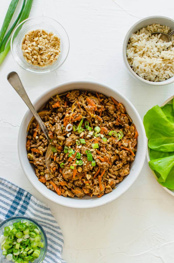 a serving bowl with asian chicken wraps filling in it