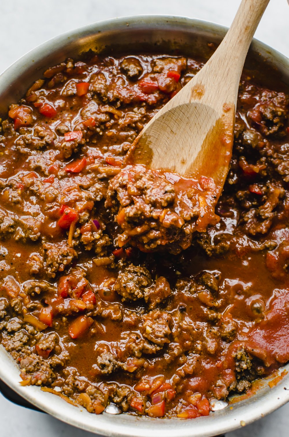 Homemade, healthy sloppy Joe mixture being scooped out of a pan with a wooden spoon. 