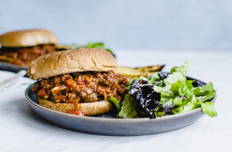 Sloppy Joe on a plate with salad next to it.