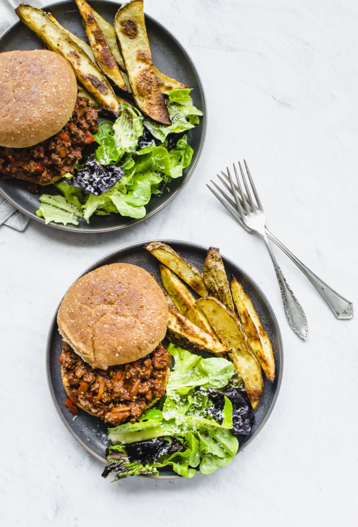 Two plates with forks and healthy sloppy joes, fries, and salad