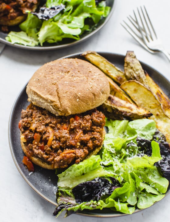 Sloppy joes on a plate with salad and steak fries