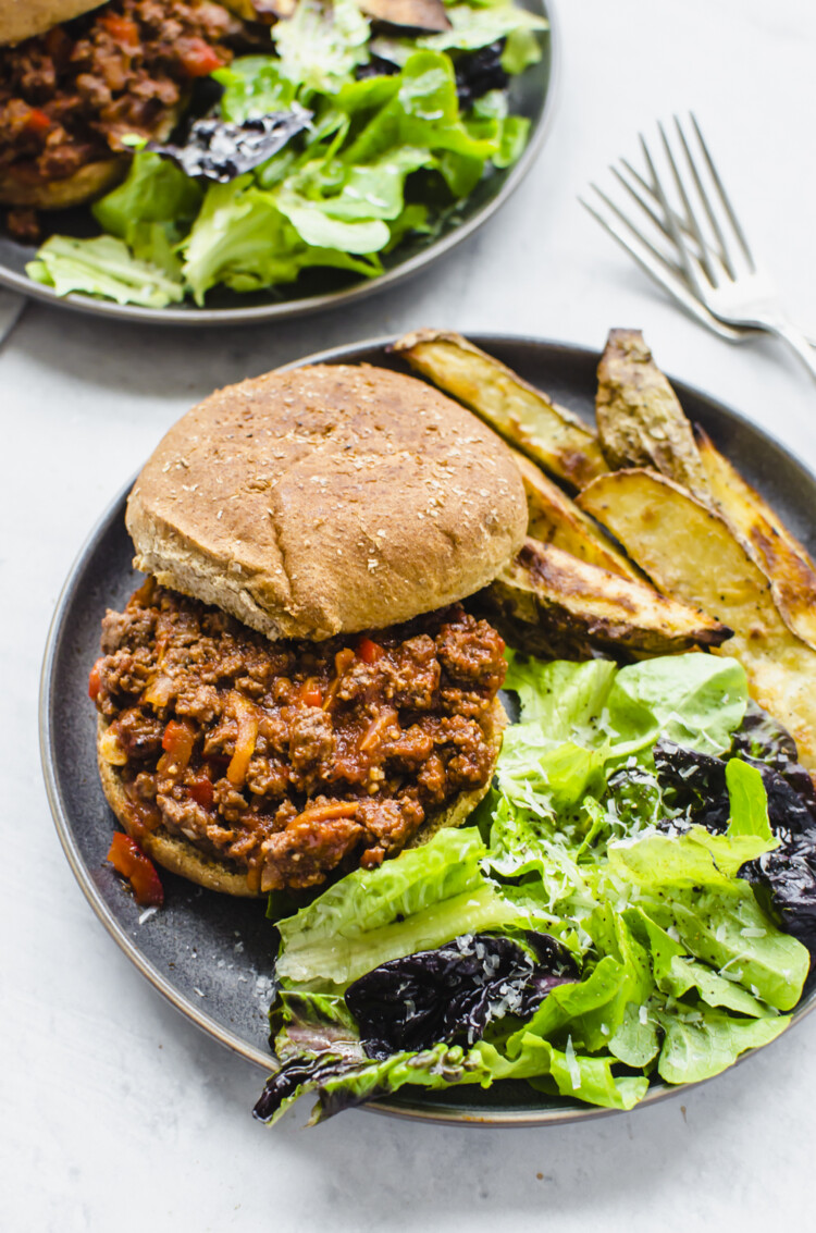 Sloppy joes on a plate with salad and steak fries