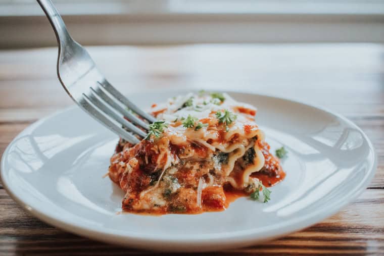 Spinach Lasagna roll with a fork on a white plate