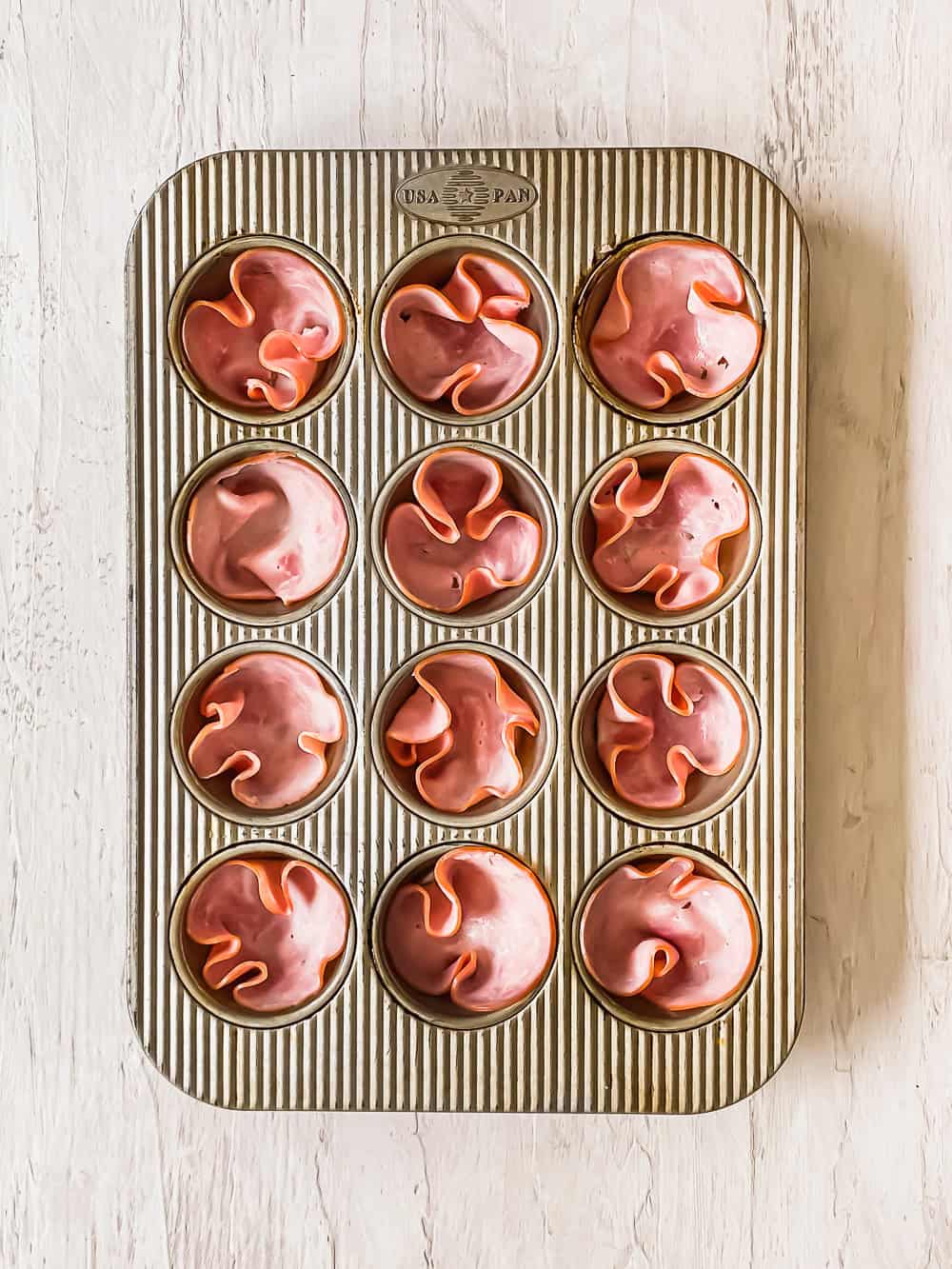 Ham slices in a muffin tin.