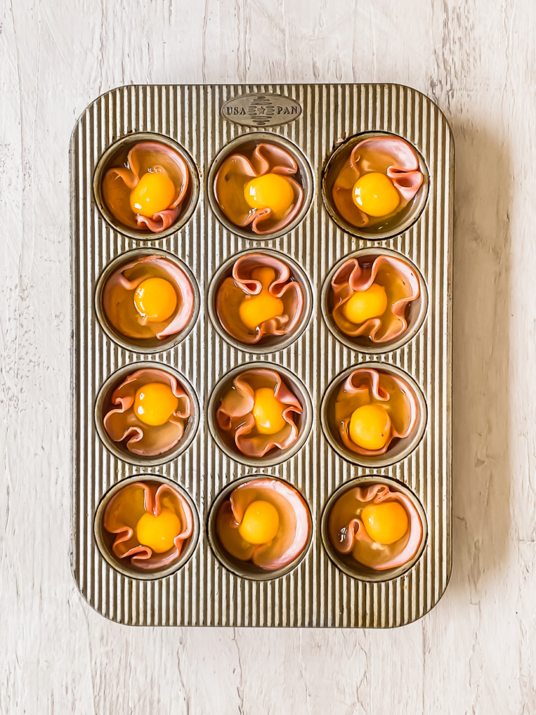 ham slices and cracked eggs in individual muffin cups