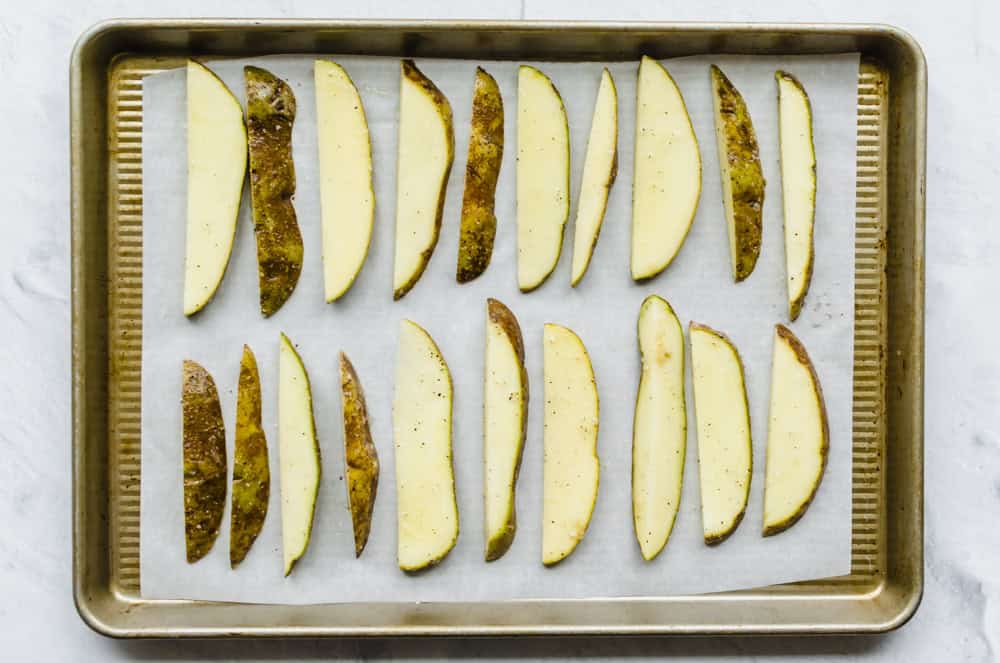 potatoes cut in the shape of steak fries on a sheet pan