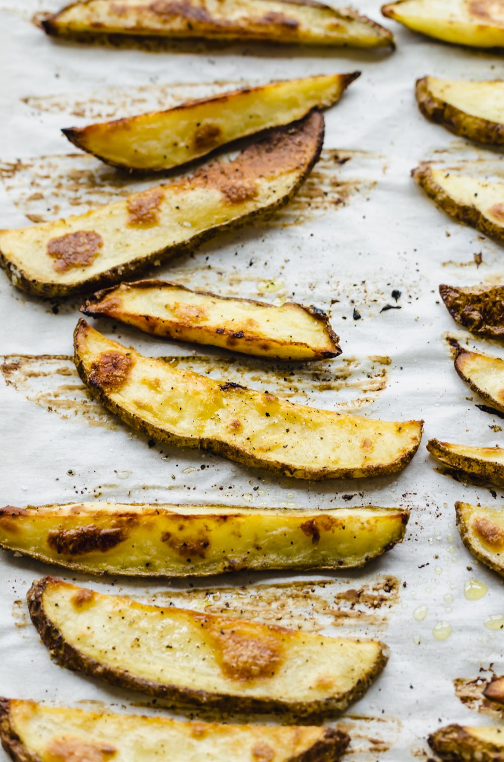 Oven roasted fries on parchment paper on a sheet pan.