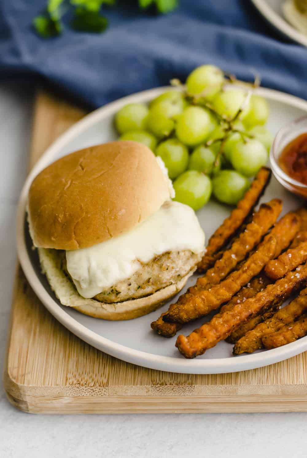 Chicken burger on a bun with cheese on a plate.