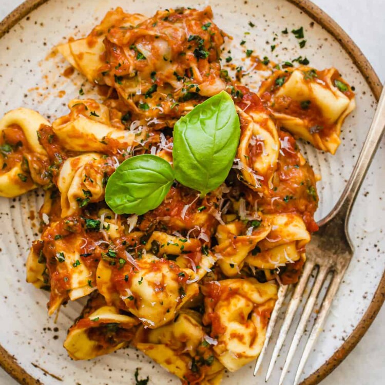 4-Ingredient Baked Tortellini served on a plate with fresh basil leaves on top.