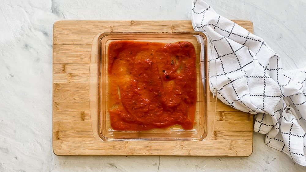 An 8x8 dish with marinara sauce covering the bottom.