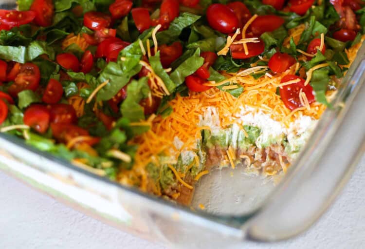 Layered taco dip with a serving missing.