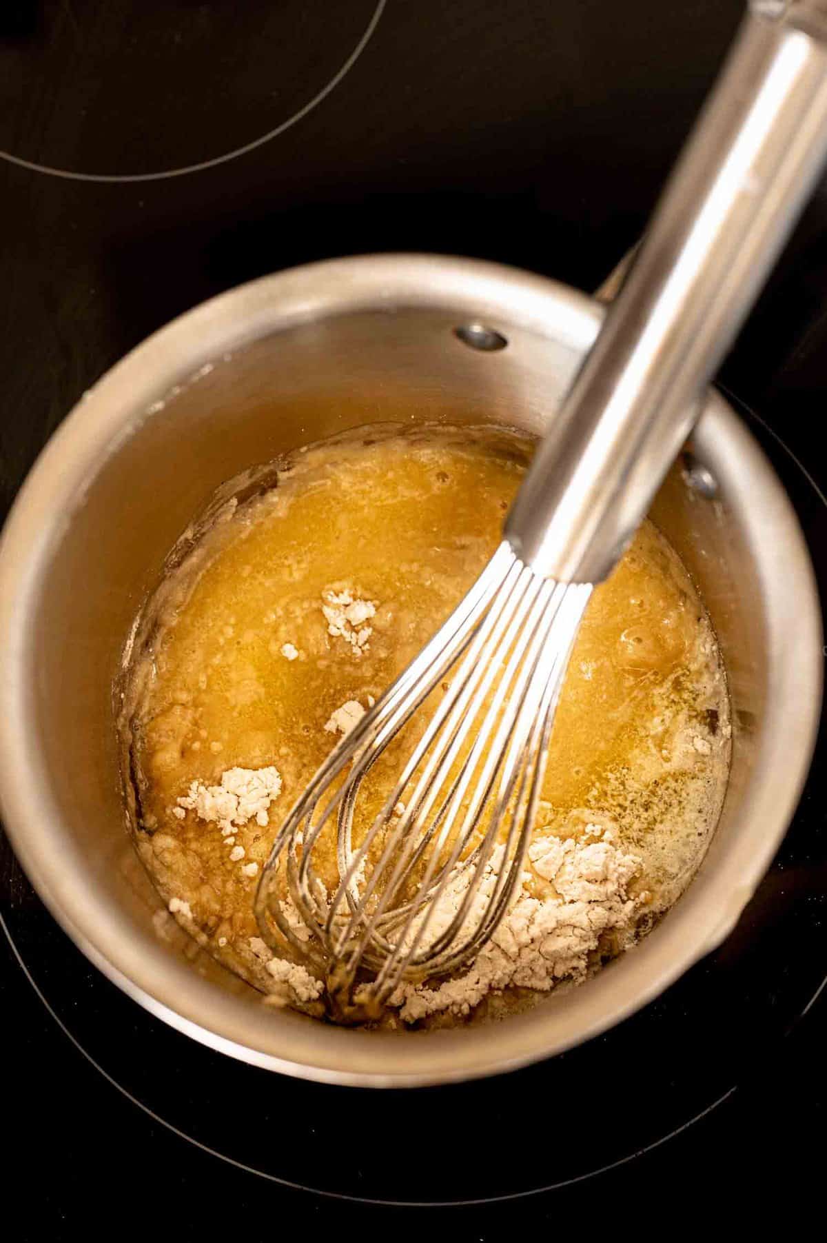 boiling ingredients for cream of chicken soup in a pot with a whisk