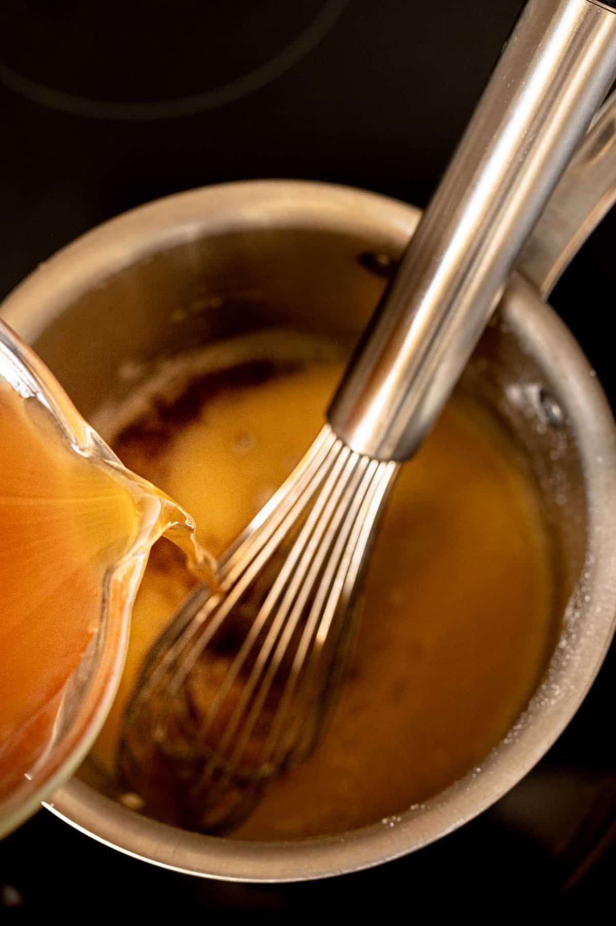 pour broth into a pot with a whisk