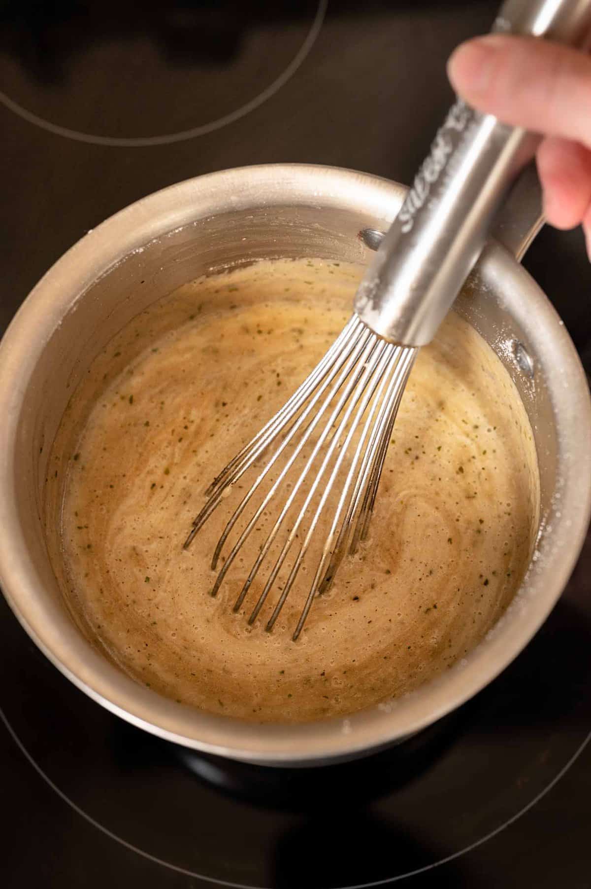 whisking broth and seasonings in a pot