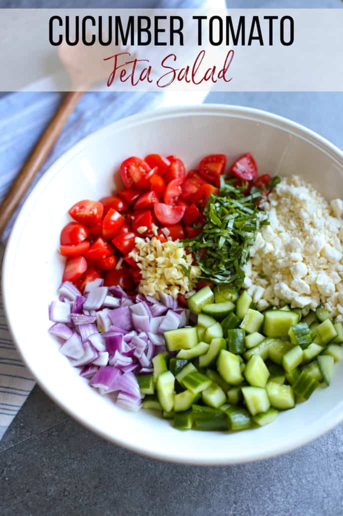 chopped cucumber, red onion, tomatoes, basil, garlic and crumbled feta in a white bowl