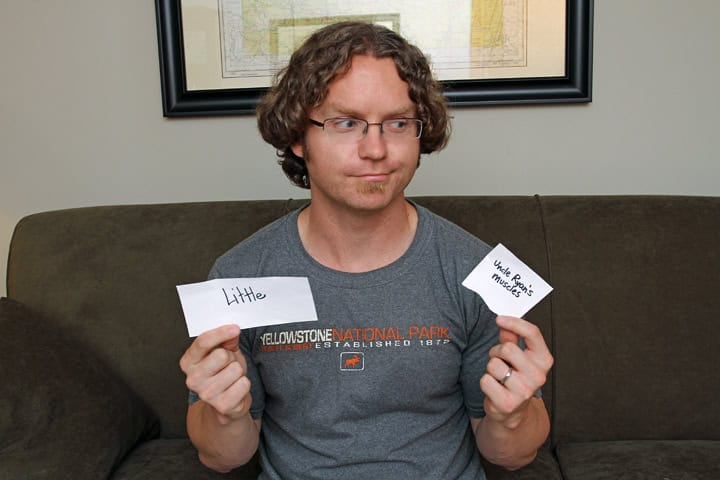 A man holding two pieces of paper while playing DIY Apples to Apples.