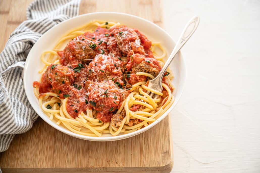 fork twirling spaghetti that is topped with meatballs and sauce