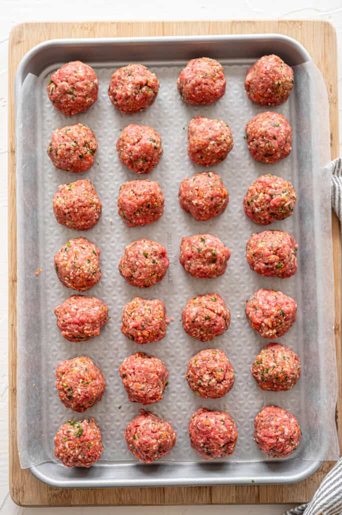 Raw meatballs on a sheet pan ready to freeze before moving to a freezer-safe container.