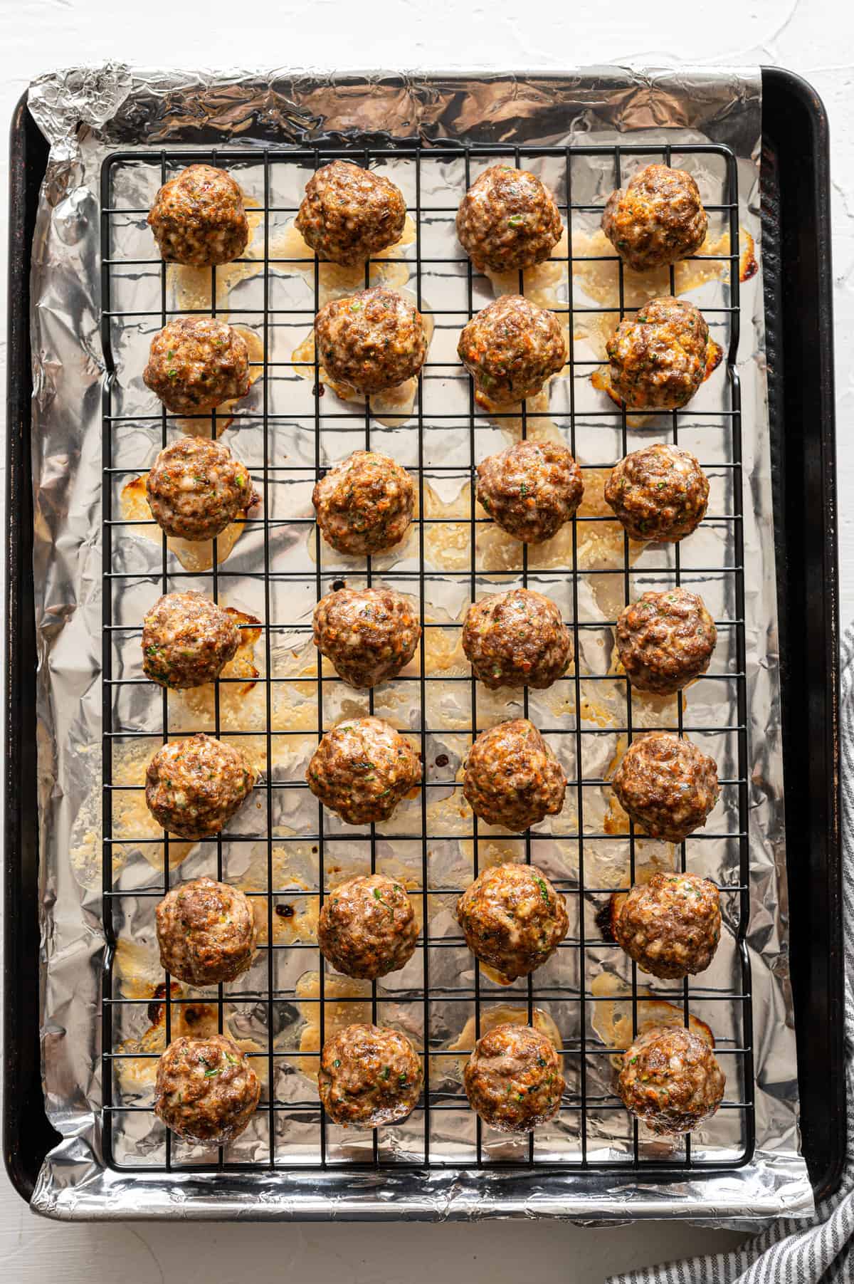 Meatballs with sneaky veggies on a rack over a baking sheet straight from the oven.