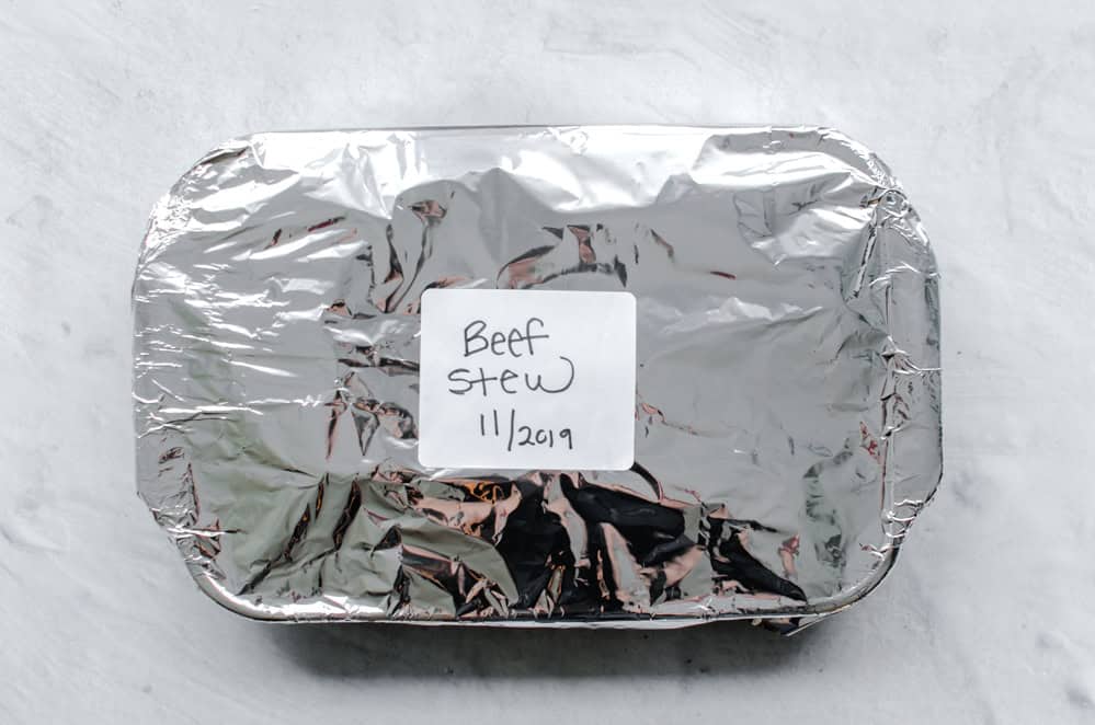 Easy beef stew in a casserole dish covered in foil and ready to be frozen.