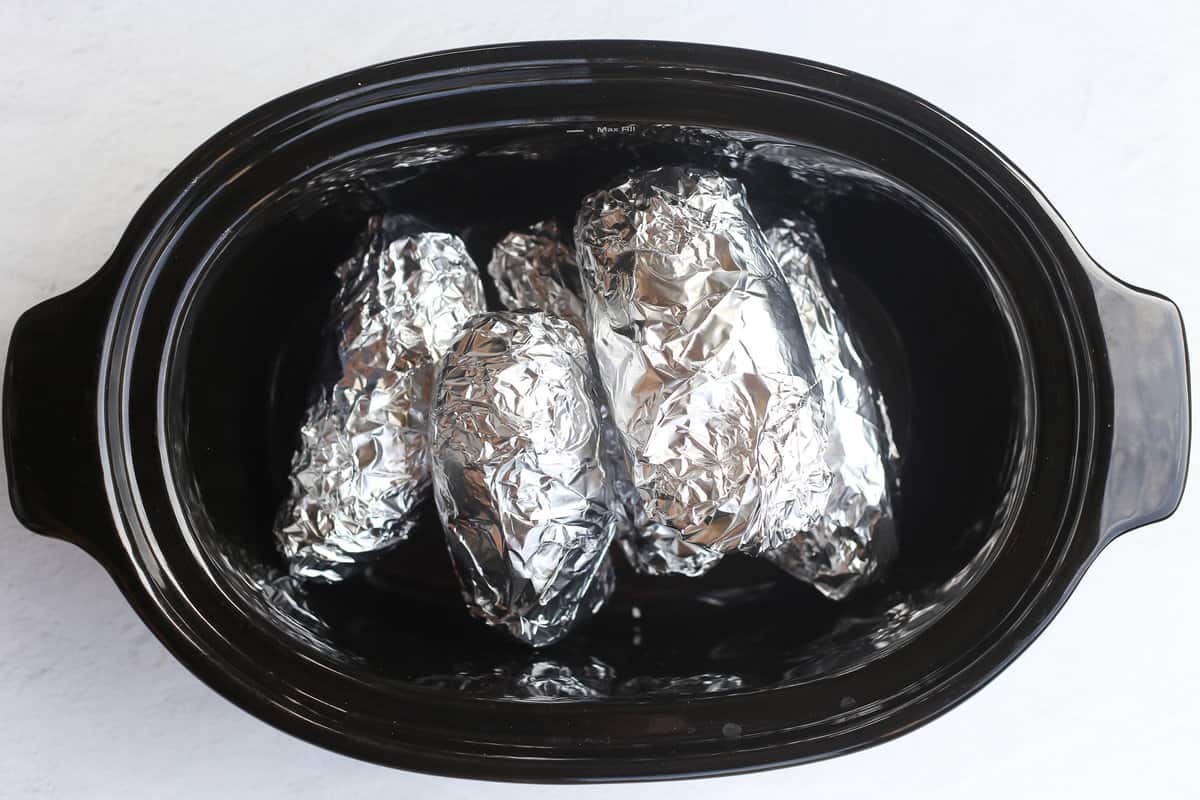Foil wrapped potatoes in a slow cooker.