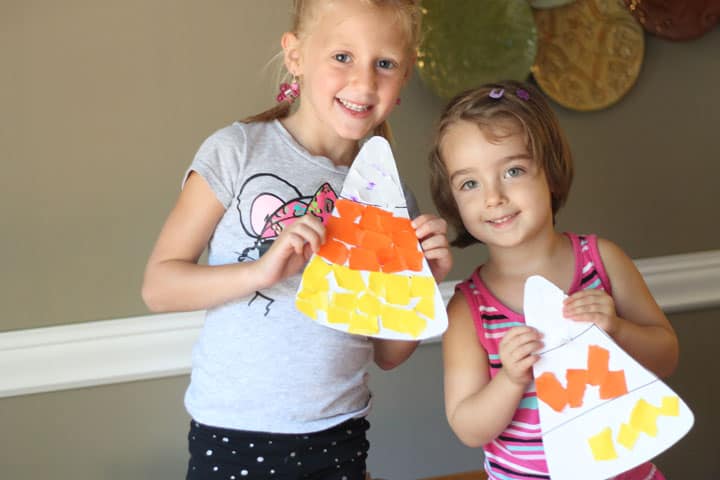 Two kids holding up their completed candy corn paper crafts.