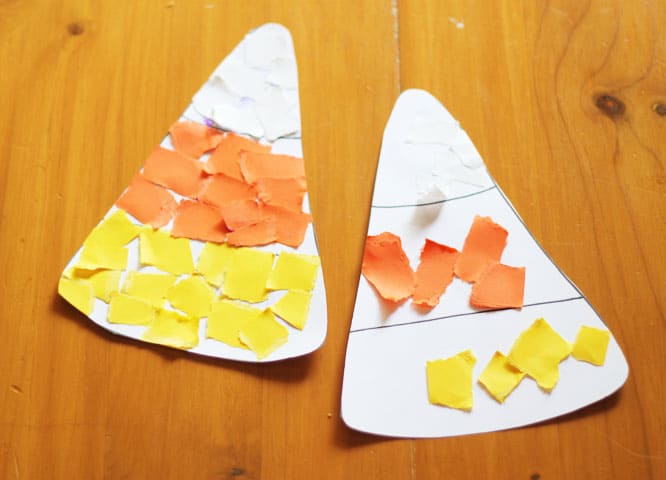 Two completed candy corn paper crafts lying side by side on a table.