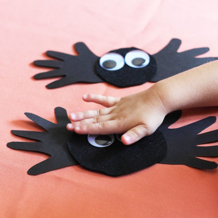 Little hands placing the eyeballs on the Handprint Spider craft. 