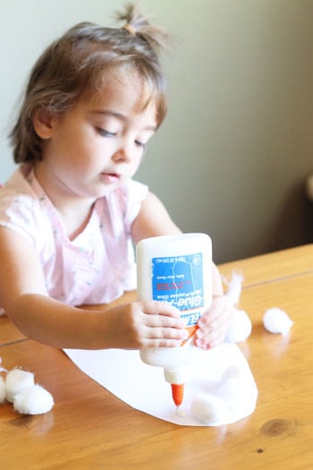 Little girl making puffy ghosts with glue and cotton balls.