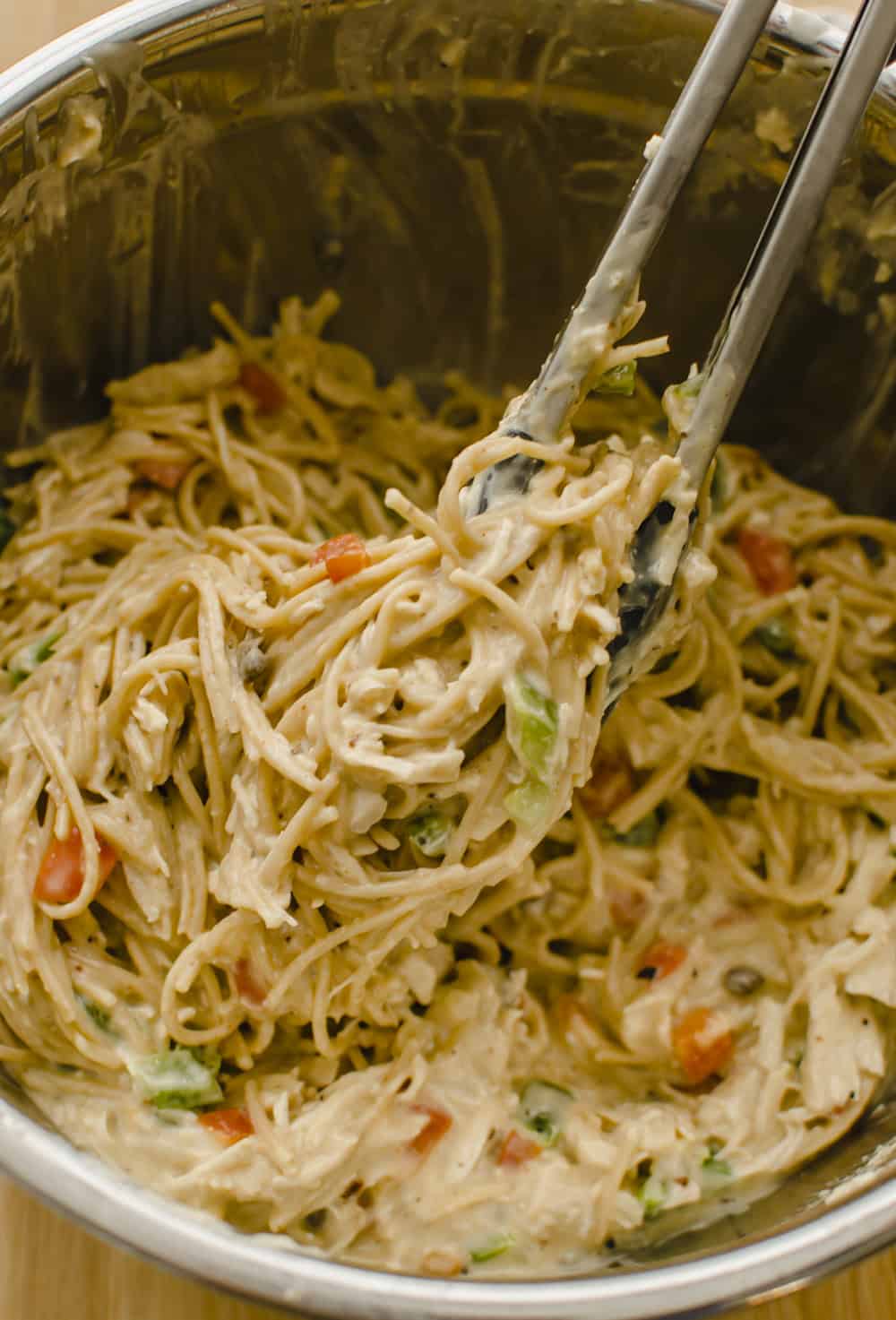 Chicken spaghetti ingredients all mixed together in a metal mixing bowl.