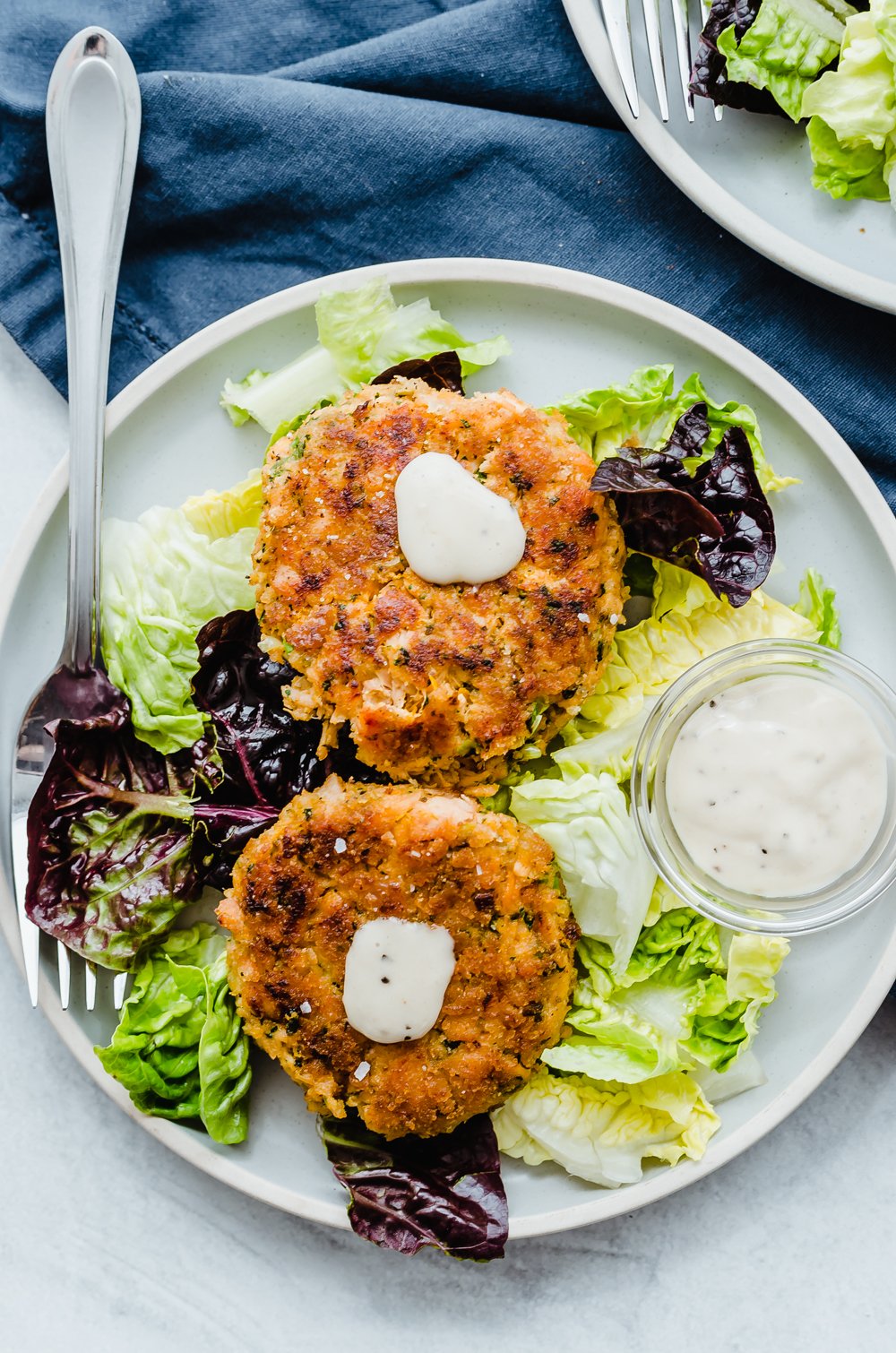 Salmon patties on a bed of lettuce with dollops of lemony avocado sauce.