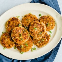 Salmon and sweet potato cakes lined up on a white serving platter.
