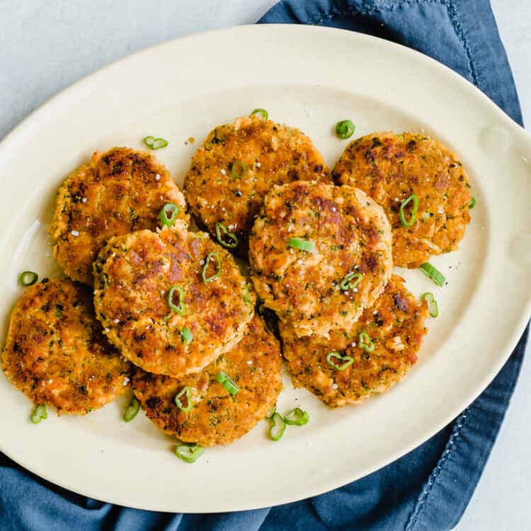 Salmon and sweet potato cakes lined up on a white serving platter.