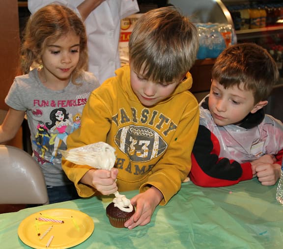 boy decorating cupcake at birthday party