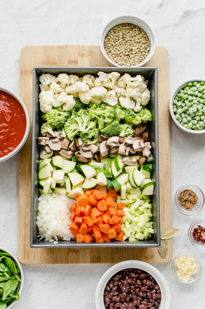 Large pan of chopped vegetables on a wooden cutting board.