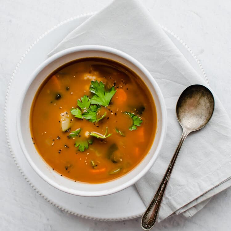 Bowl of vegetable soup in a white bowl with a spoon