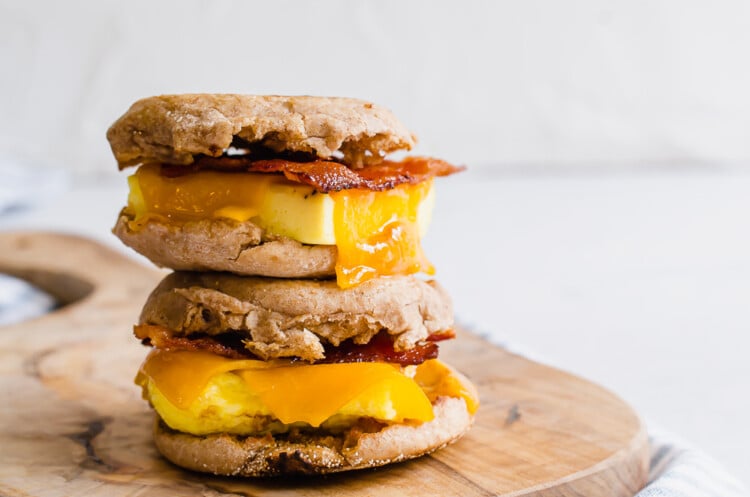 Make ahead breakfast sandwiches stacked on a cutting board.