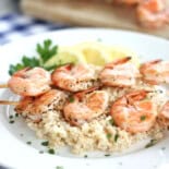 Grilled Mediterranean shrimp skewers sitting on a bed of rice.