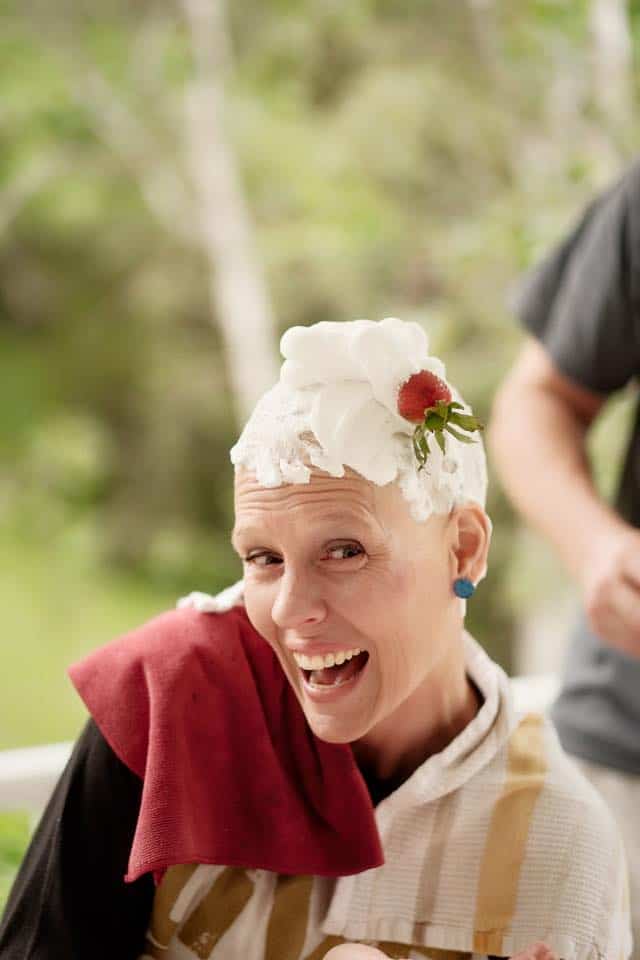 Darcie with shaving cream on her head and a strawberry stuck in it.