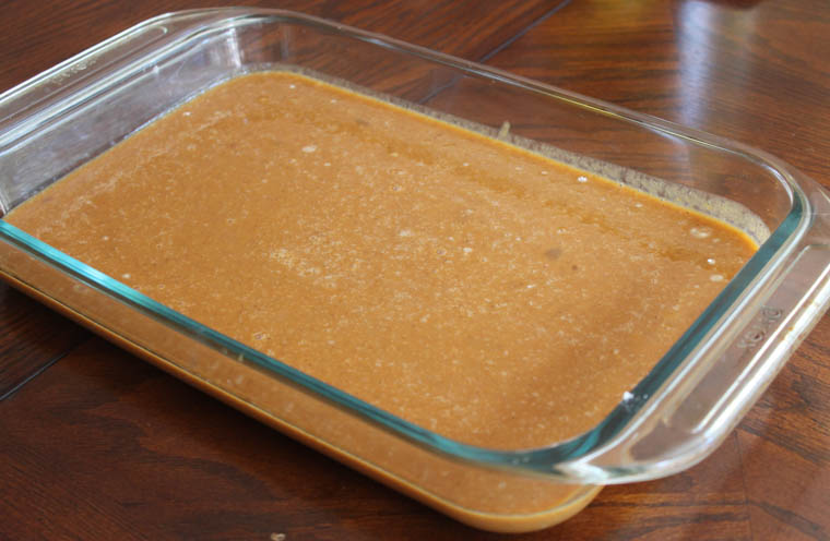 The base of pumpkin dump cake in a glass baking dish. 