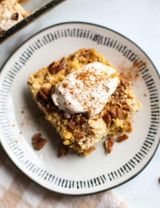 Pumpkin dump cake served on a plate with whip cream on top.