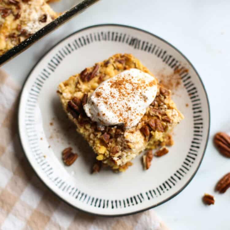 Pumpkin dump cake served on a plate with whip cream on top.