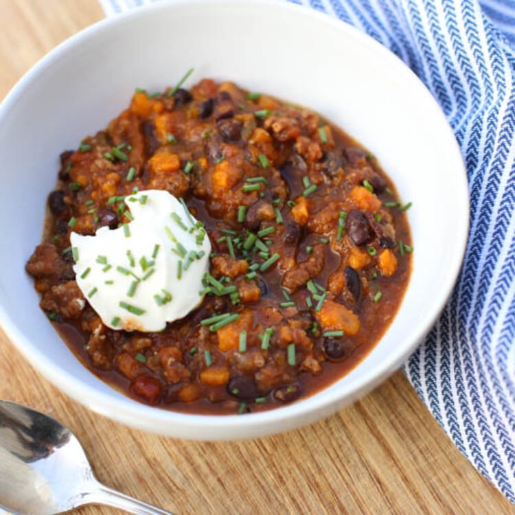 Healthy Turkey Chili with Sweet Potatoes and Black Beans served in a white bowl with a dollop of sour cream.
